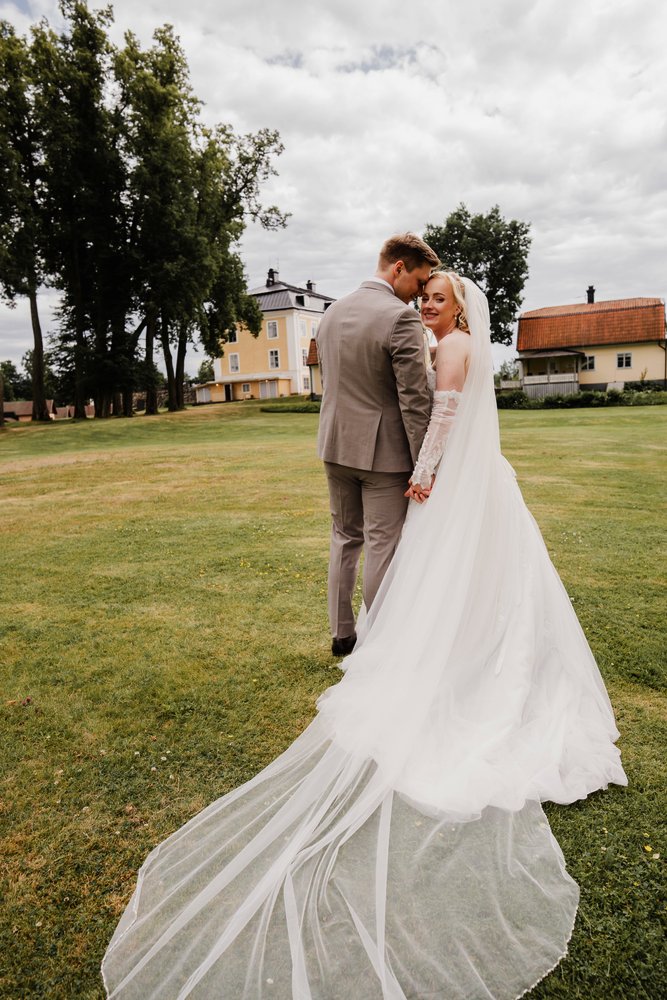 Marte og Marius på plenen foran herregården, med det lange sløret bak seg